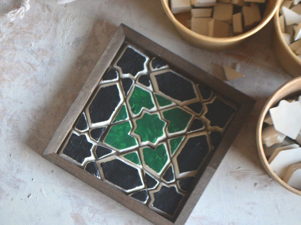 A green and black geometric coaster in a dark wooden frame